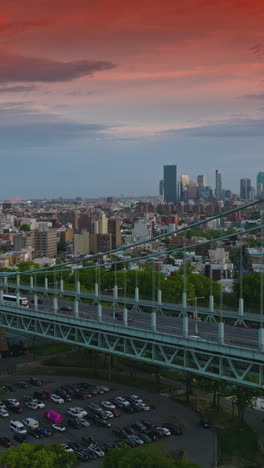 impressive red sky over the huge metropolis. busy traffic on the triborough bridge in new york. evening falling on the city. vertical video