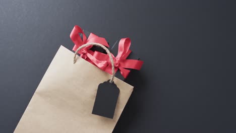 video of gift bag, gift tag and gift boxes with red ribbon and copy space on black background