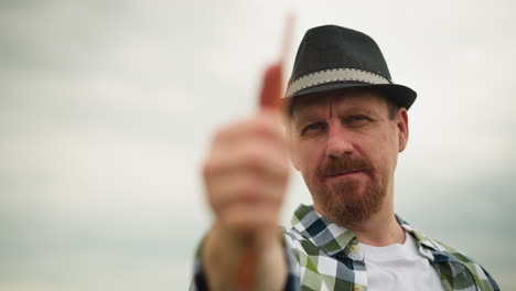 close-up of a sculptor in a checked shirt and hat, holding a brush with intense focus, against a blurred background