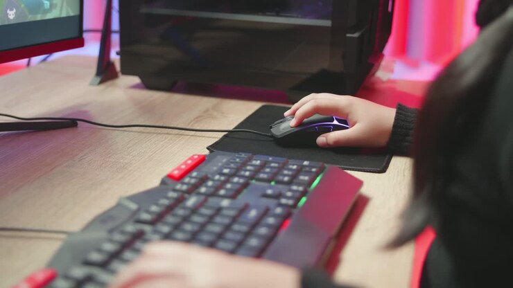 Hænder på en pige, der bruger tastaturet til at spille computerspil