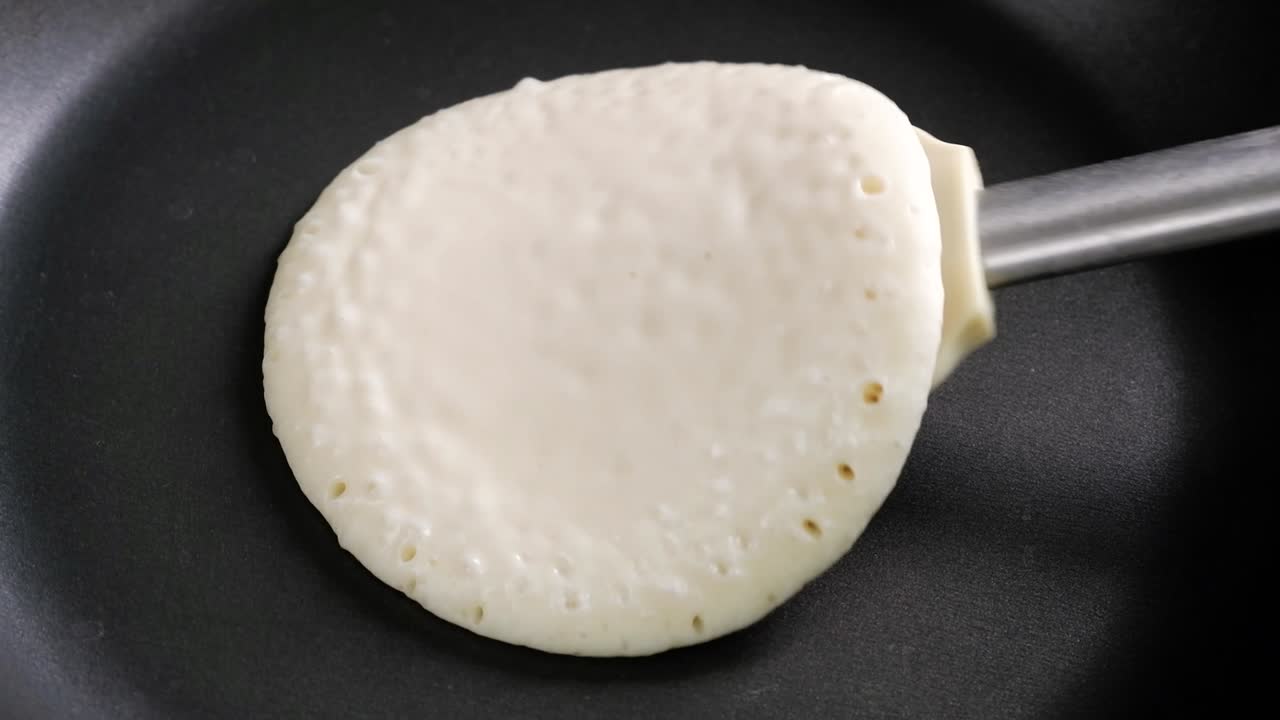 Yakın çekim pankek, spatula ile çevrilerek tavada kızartılıyor
