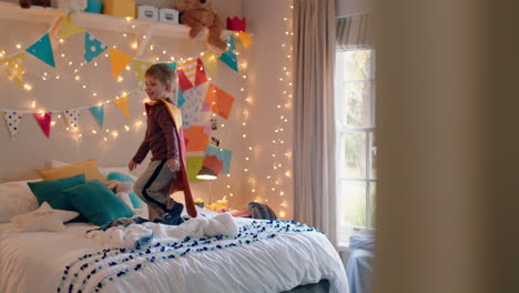 niño feliz saltando en la cama vestido con disfraz jugando a un juego disfrutando de la imaginación lúdica en un dormitorio colorido en casa