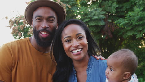 Portrait-Of-African-American-Family-With-Baby-Daughter-Relaxing-In-Garden-At-Home-Together