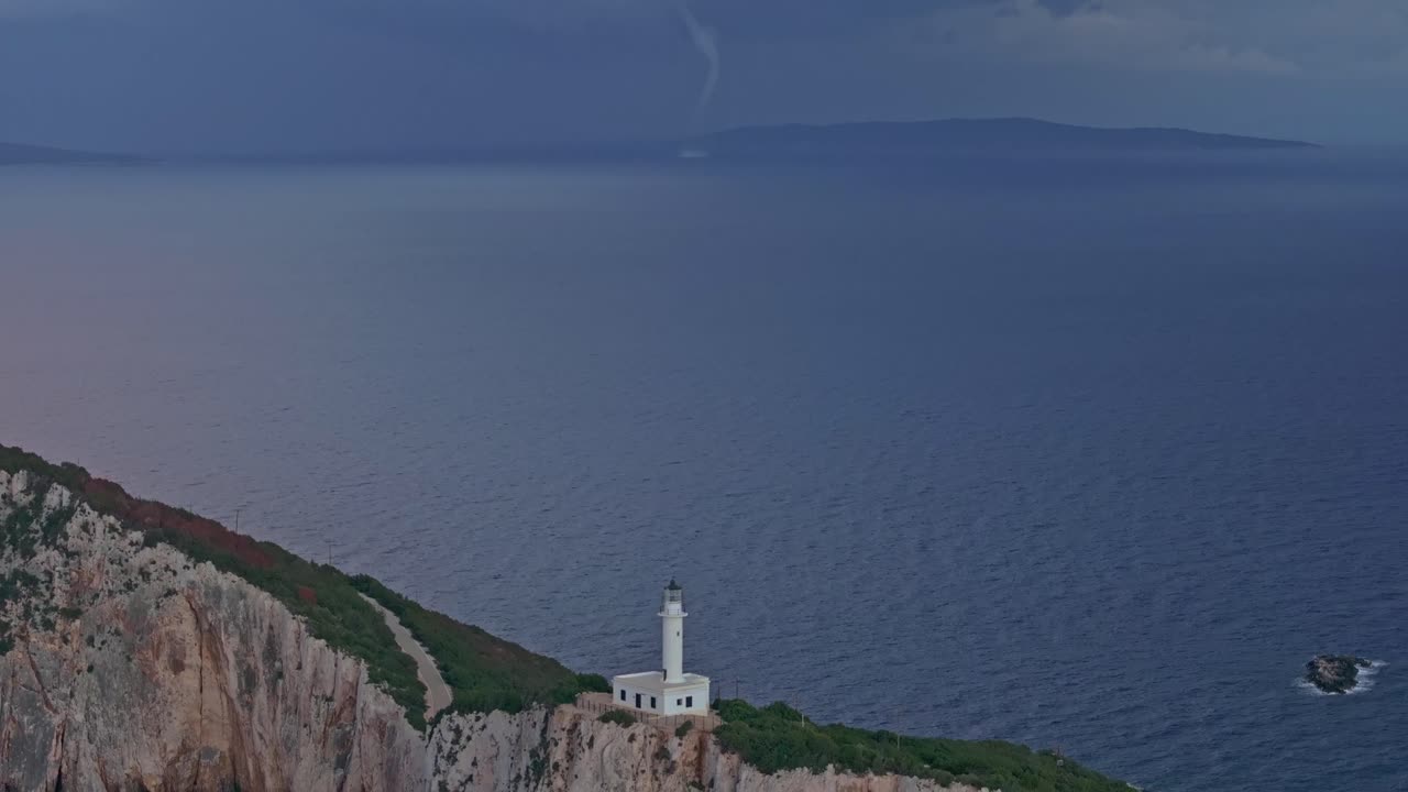 Il faro a Capo Lefkatas fronteggia un tornado marino e le scogliere al crepuscolo, Lefkada, Grecia