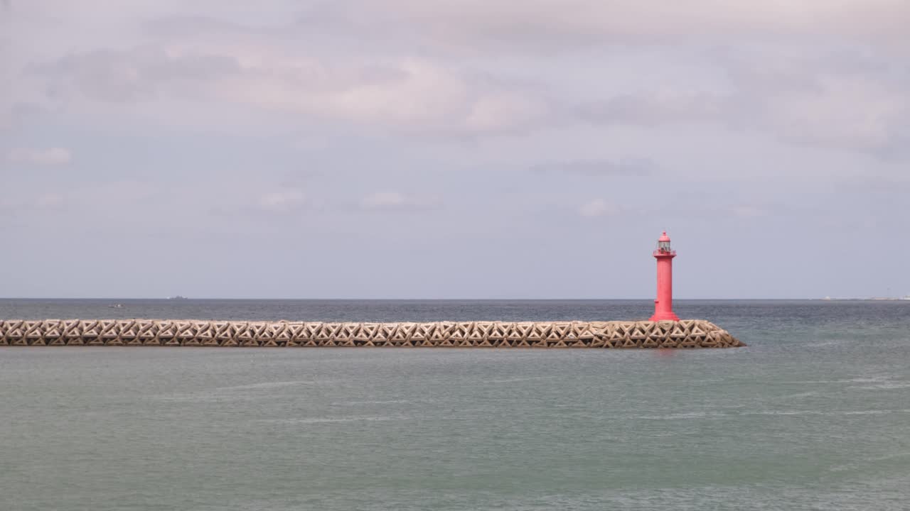 faro de gran angular en el muelle rodeado de interminables aguas oceánicas