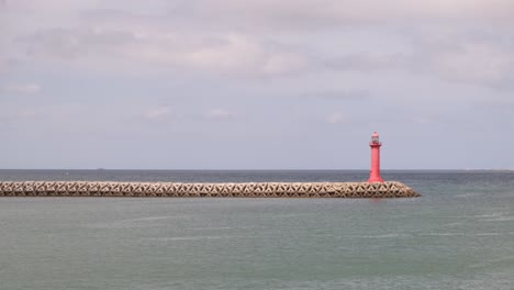 faro de gran angular en el muelle rodeado de interminables aguas oceánicas