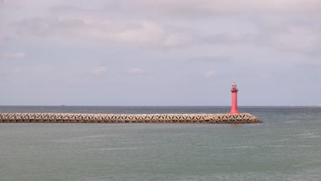 wide angle shot lighthouse on pier surrounded by endless ocean water