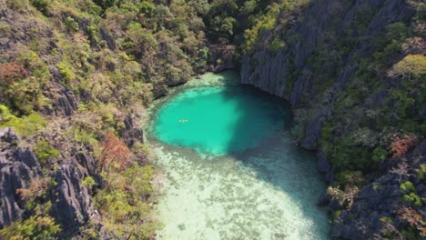 video de dron de 4k volando hacia una pareja en kayak en la laguna verde mientras está en una gira desde coron en palawan, filipinas, puede ver la increíble naturaleza desde los altos acantilados de piedra caliza hasta el azul del agua del océano