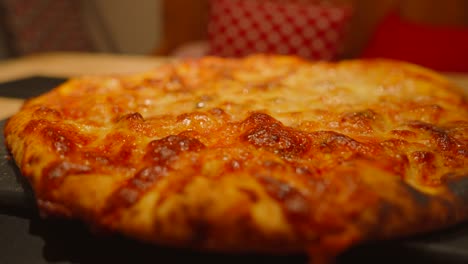 rotating shot around delicious italian cheese and tomato margherita pizza food on table ready to be sliced into pieces to eat.
