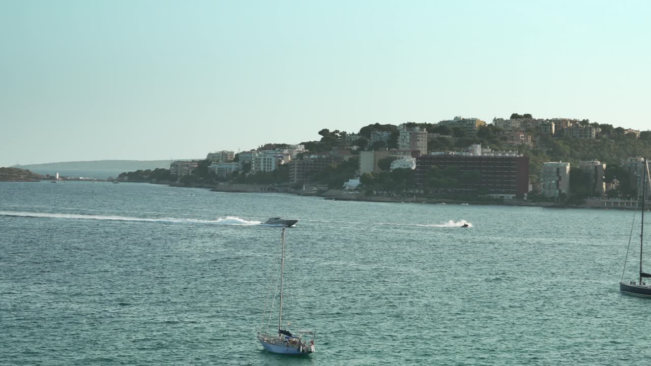 Motoscafo e moto d'acqua che attraversano le acque costiere a Cala Major, Maiorca