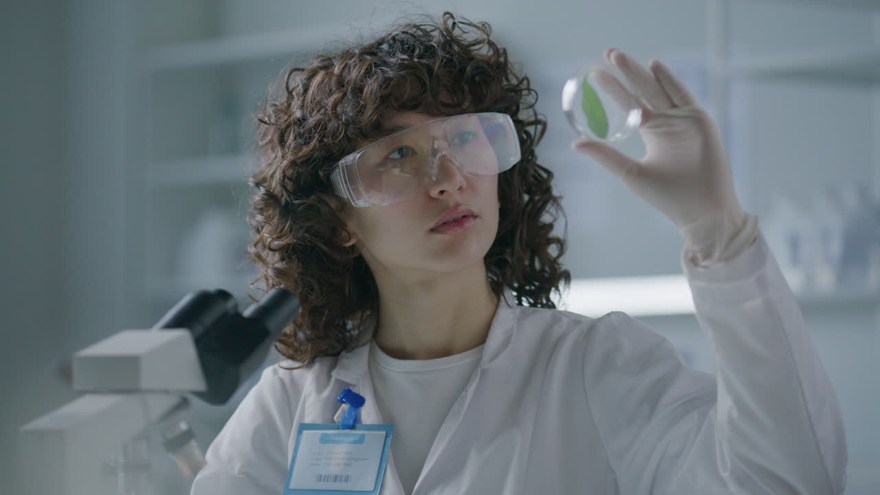 Female Scientist Examining Leaf in Petri Dish during Laboratory Research