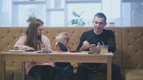 lady-kisses-child-in-coloured-pullover-and-father-triumphs