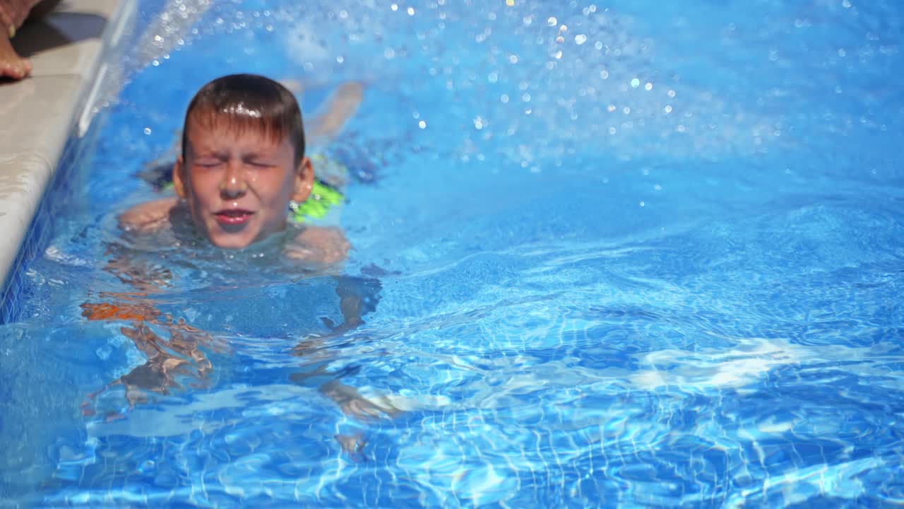 Boy in the pool outdoors. Cute boy showing his mother his underwater swimming in summer. Teenager in the swimming pool. Close-up.