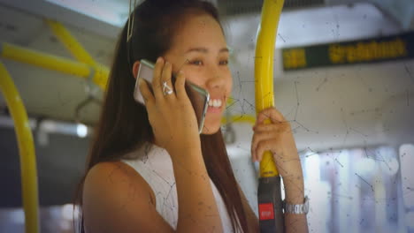 woman using smartphone standing inside bus, displaying technology graphics with green data speckles