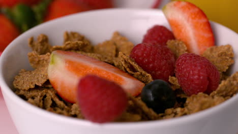 Beeren-Gießen-In-Müslischale-Am-Frühstückstisch