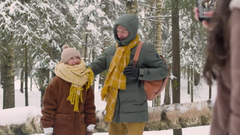 rear view of a woman taking a photo of her husband and daughter in the snowy forest 1