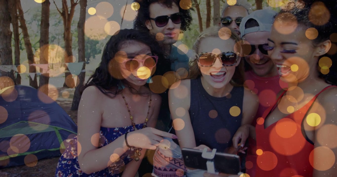 Amici che portano il telefono su un'asta per selfie, si avvicinano visualizzando lo scatto per i social media con sovrapposizione bokeh