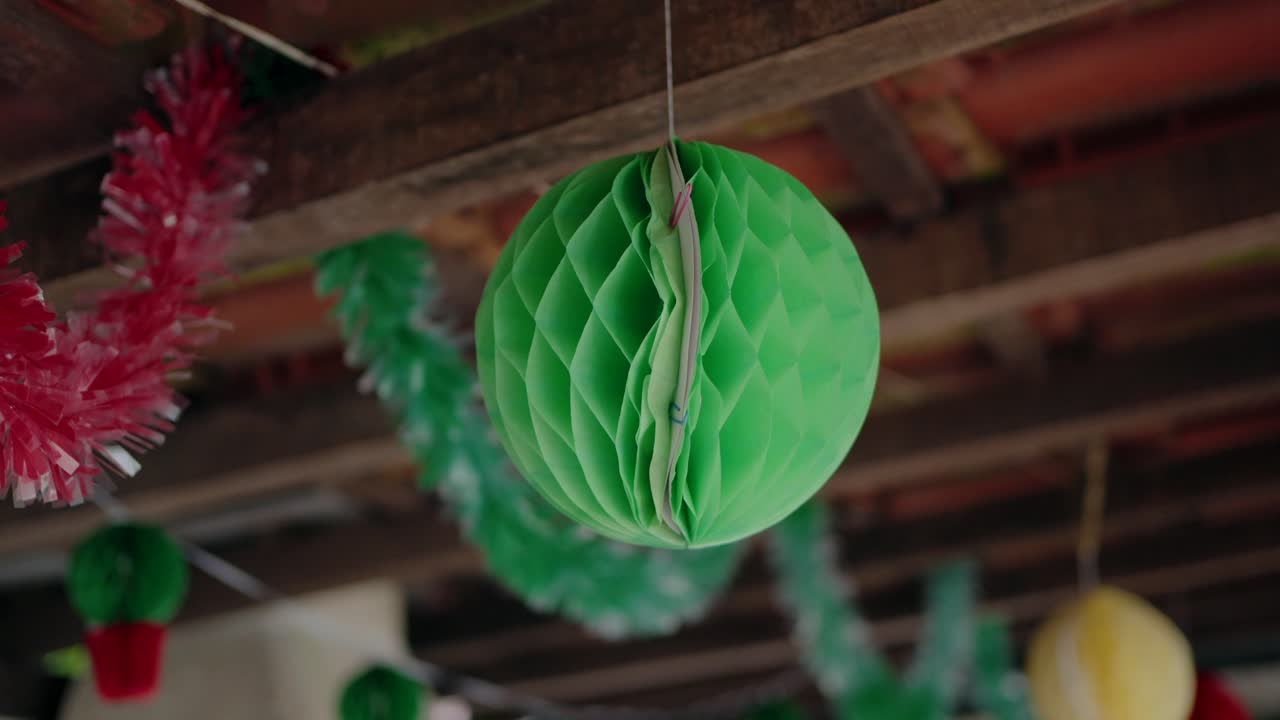 Decoraciones coloridas para una fiesta de Santos Populares, con adornos colgantes de papel verde y rojo y espumillón