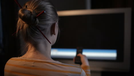 Woman-sitting-in-front-of-TV-set-and-changing-channels-quickly