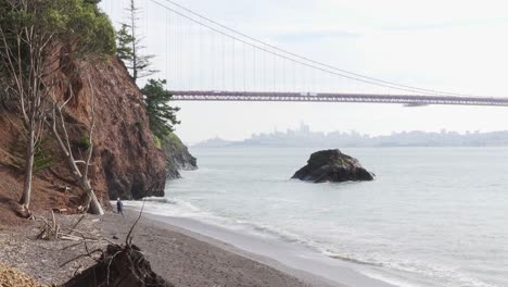 young girl walking along the sea shore with san francisco and golden gate bridge in the background