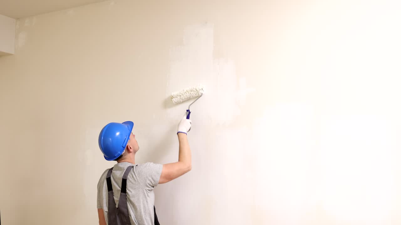 Man Painting a Wall with a Roller during Home Renovation