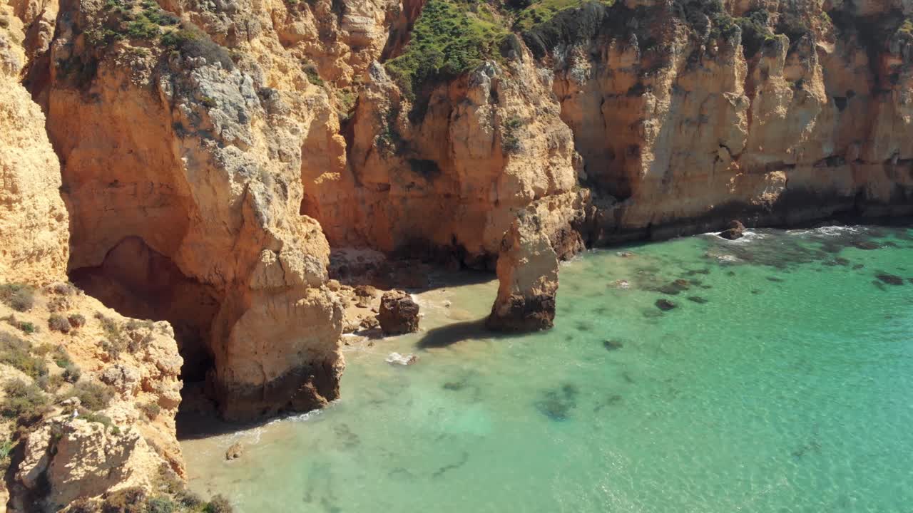 Acantilados escarpados y aislados del sur del Algarve bañados por un mar verde esmeralda, Portugal - Toma de seguimiento aérea a baja altura.