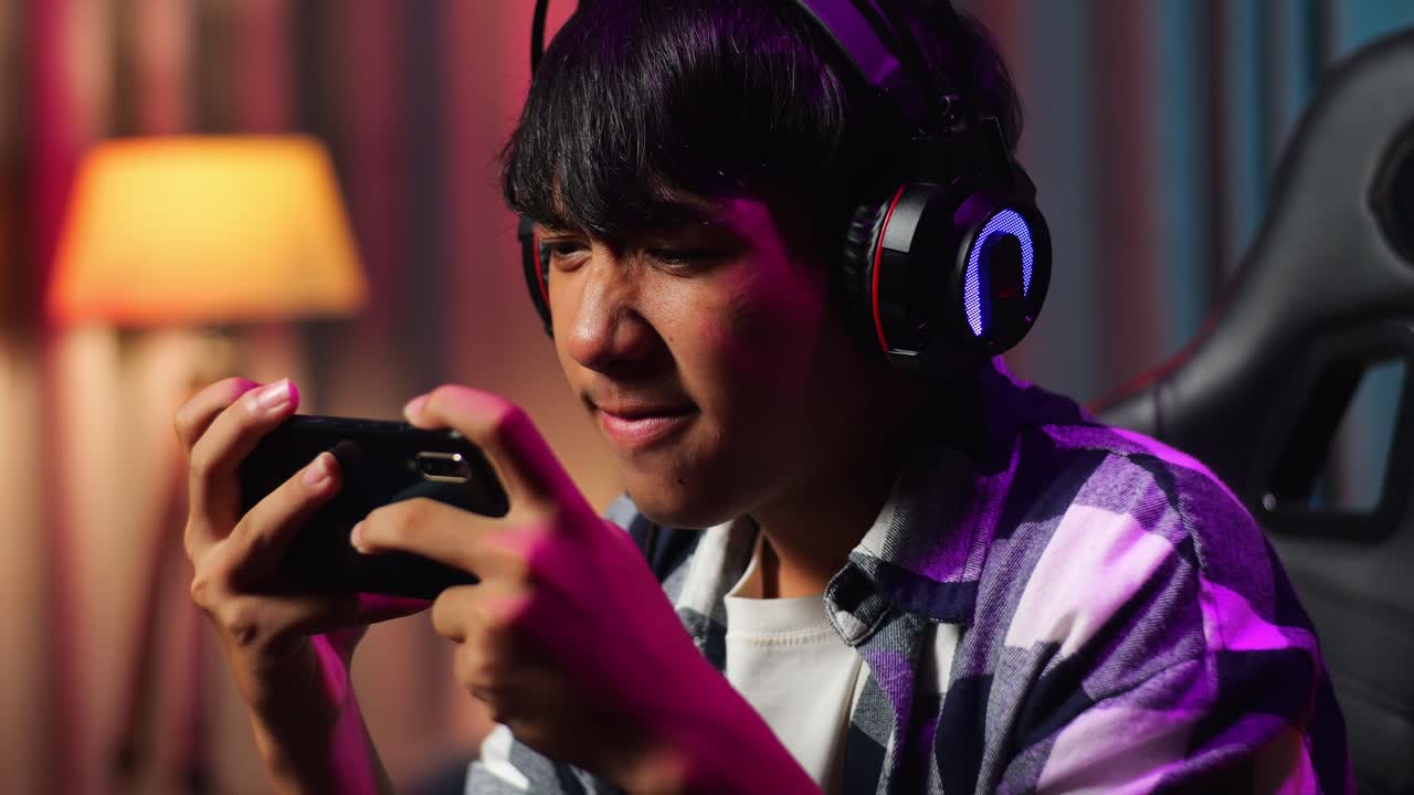 스마트폰에서 비디오 게임을 하는 심각한 아시아 십대 소년 게이머의 근접