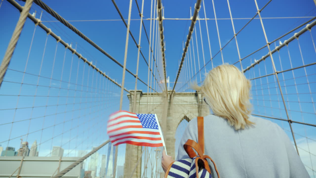 una mujer con la bandera de américa en la mano está en el puente de brooklyn