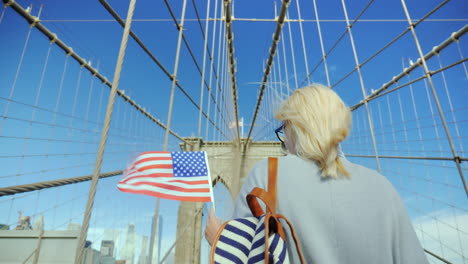 a woman with the flag of america in her hand is on the brooklyn bridge