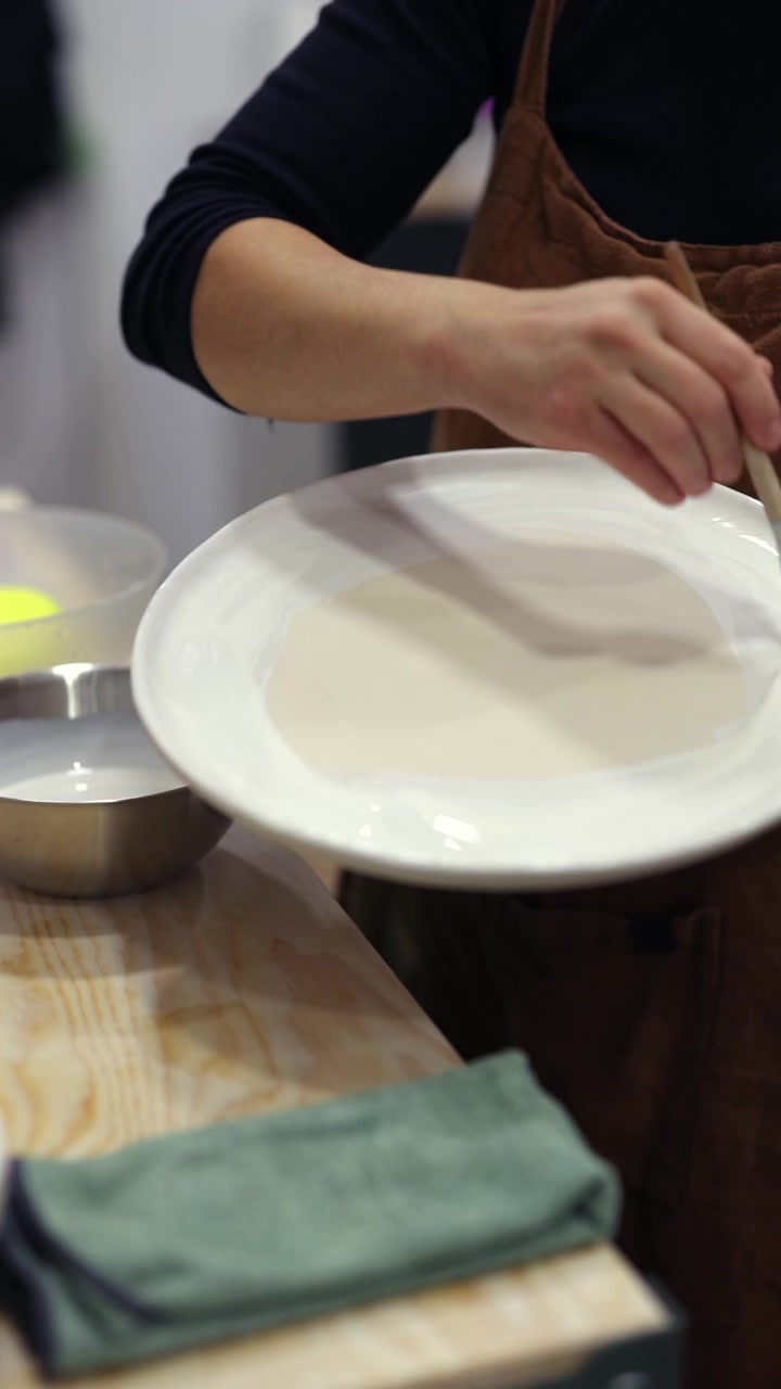 Potter Applying Glaze to Ceramic Plate in Studio