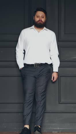 man standing against a dark paneled wall