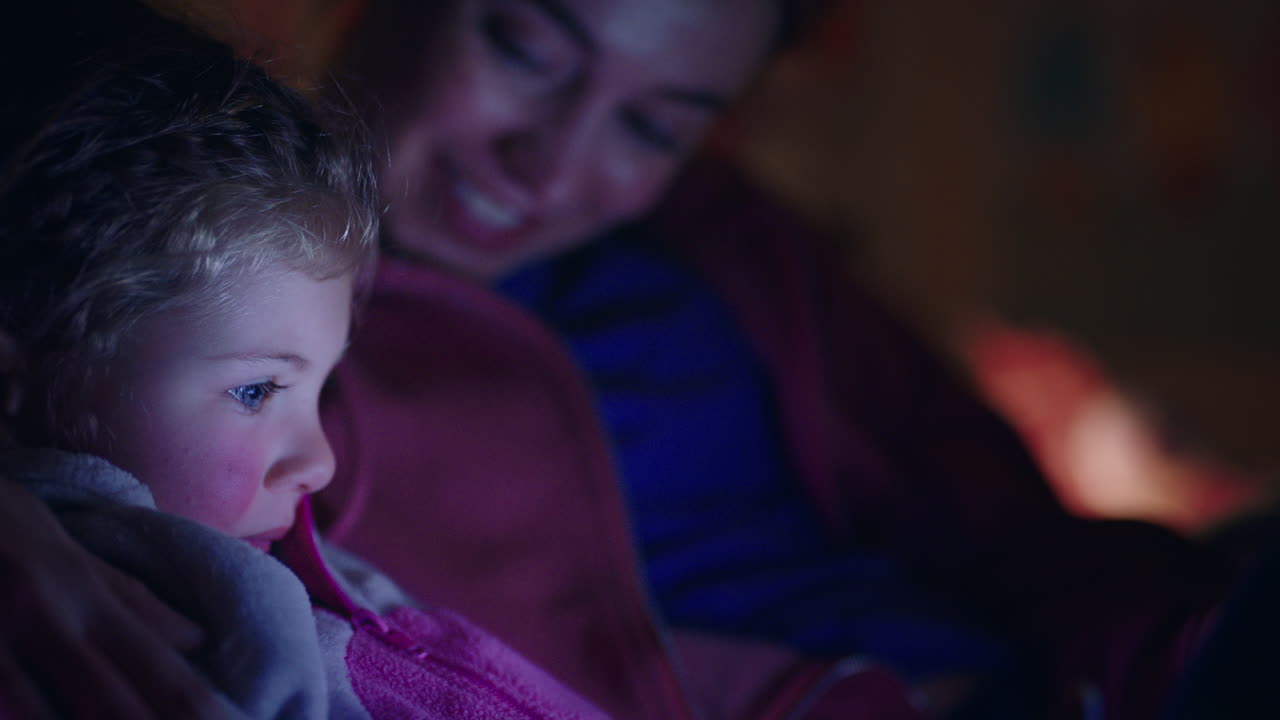 mother and child using tablet computer mom teaching little girl playing games on touchscreen technology having fun before bedtime