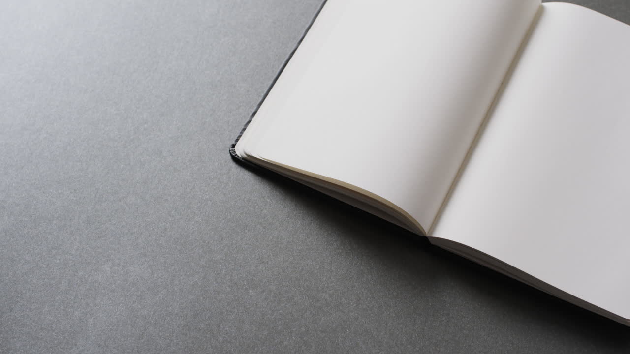Close up of open blank book with copy space on gray background in slow motion