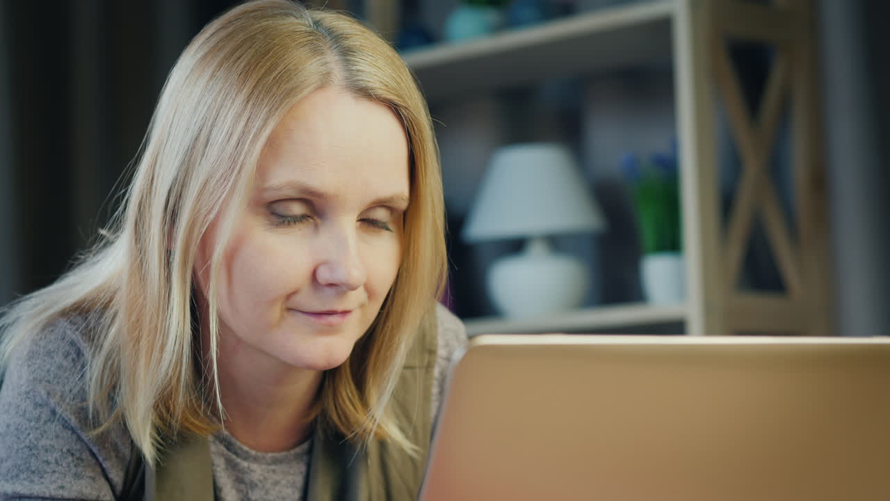 una mujer de mediana edad usa una computadora portátil en su cama 4