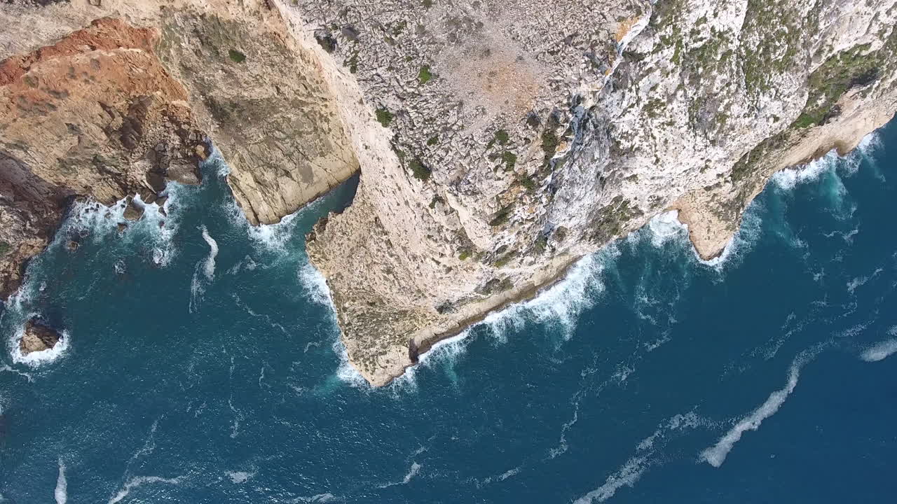 Aerial view of Cape San Antonio, Denia, Valencia. Rocky cliff revealing sea waves crushing on the coastline. Blue water in a sunny day
