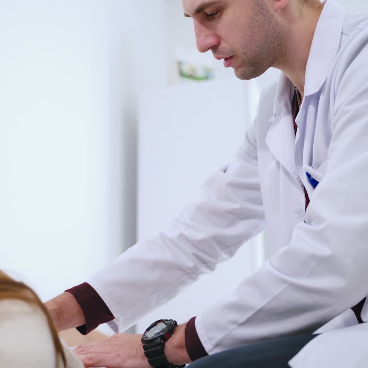 Male doctor diagnoses woman's spine. Physiotherapist is doing check up of patient's back in clinic. Female patient lying on medical bed. Health care concept.