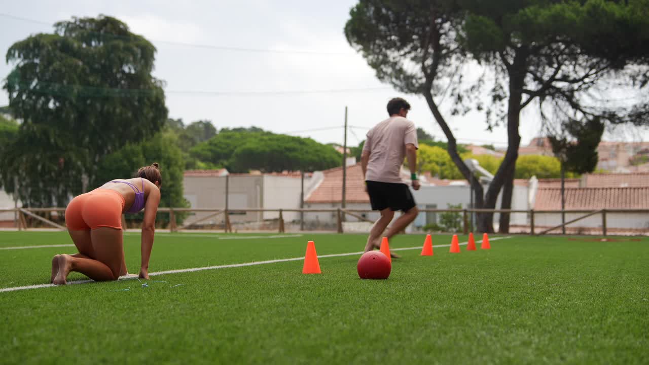 People Exercising Outdoors on Grass with Cones and Ball