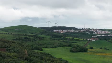drone shot over hill with windmills and small town