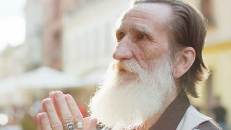 old man with white beard praying on the street