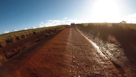 punto de vista desde la parte delantera de un vehículo siguiendo a una camioneta en un camino de tierra lleno de baches en molokai hawaii desde maunaloa hasta hale o lono