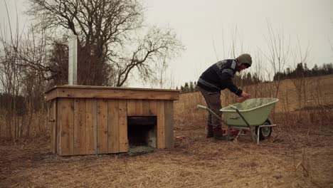 the man is transferring the leftover bricks from the diy hot tub into the wheelbarrow - static shot