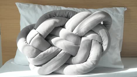 grey knotted decorative pillow on a bed