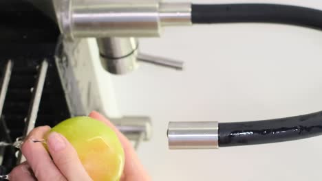 close-up of a woman washing fruit in the sink in the kitchen. fresh fruit from the supermarket. vertical video