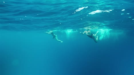 Two-women-swimming-in-deep-blue-ocean