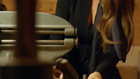 Female-shoemaker-cutting-boot-sole-working-on-old-fashioned-workshop-machine,-Close-up