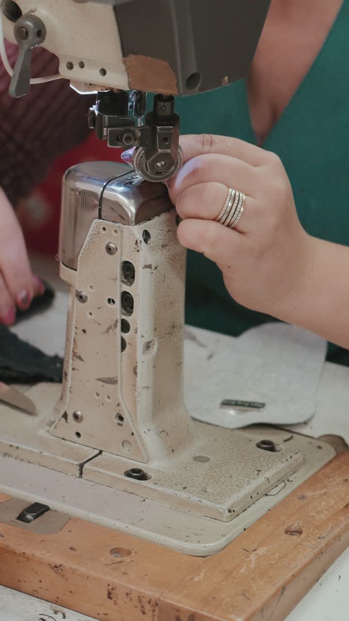 Vertical closeup of artisan inserting thread into sewing machine needle