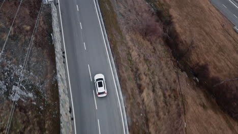 aerial overview of white car driving on empty mountain road