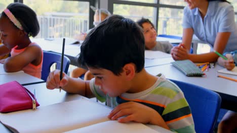 Glückliche-Schulkinder-Interagieren-Mit-Dem-Lehrer-Am-Schreibtisch-Im-Klassenzimmer-4k