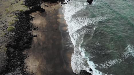 aerial of people walking on skarðsvík beach and coastline in snaefellsnes national park in iceland