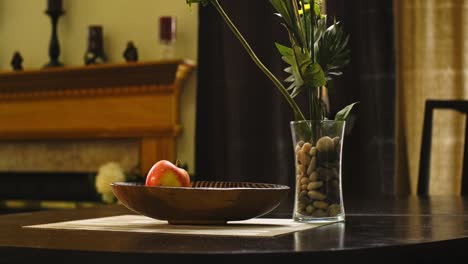 Medium-shot-of-an-African-American-man-putting-apples-in-a-wooden-bowl-on-a-dining-table